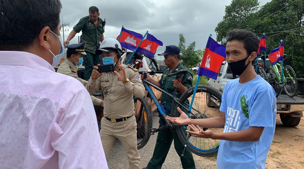 Para pencinta lingkungan berdiskusi dengan polisi yang memuat sepeda mereka ke dalam truk. Seorang petugas polisi memotret kejadian