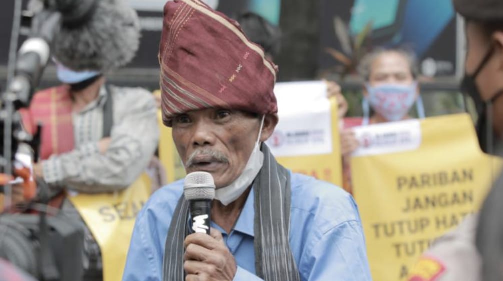 Seorang laki-laki Batak dengan tutup kepala khas dan mikrophone