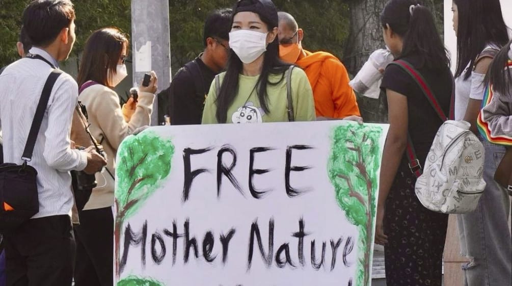 Mother Nature Activist! Seorang aktivis mengangkat plakat menghadap kamera dengan tulisan „Free Mother Nature Activist!