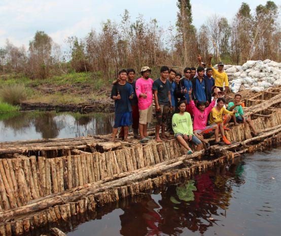 Aktivis lingkungan berdiri di atas bendungan yang mereka bangun dari kayu untuk mensekat kali.