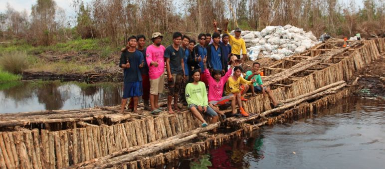 Aktivis lingkungan hidup mensekat kali untuk menghindari air mengalir keluar lewat kanal. Aktivis lingkungan berdiri di atas bendungan yang mereka bangun dari kayu untuk mensekat kali.