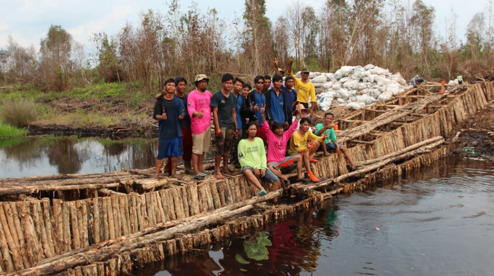 Aktivis lingkungan berdiri di atas bendungan yang mereka bangun dari kayu untuk mensekat kali.